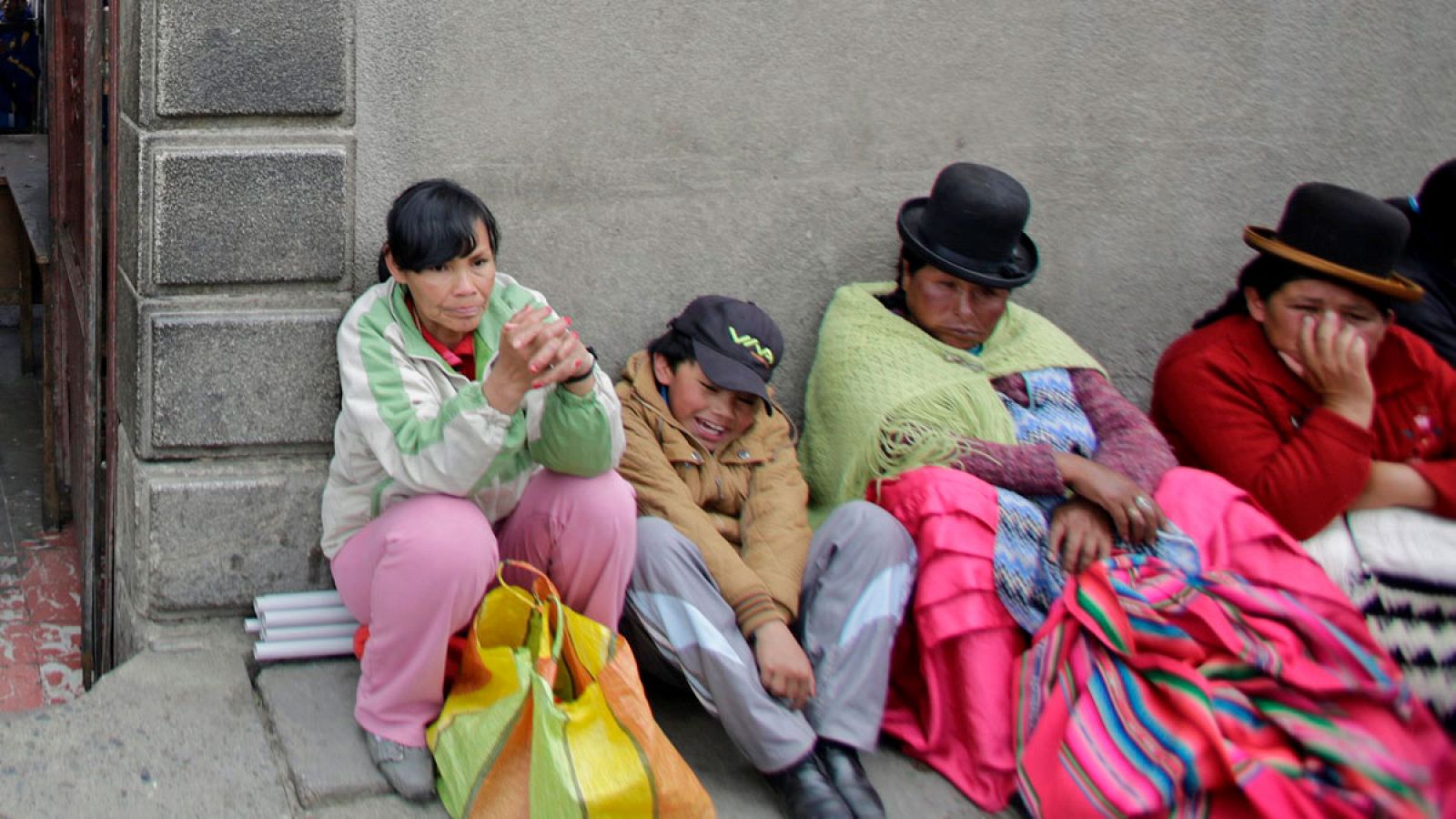 Unas mujeres bolivianas esperan sentadas en la calle