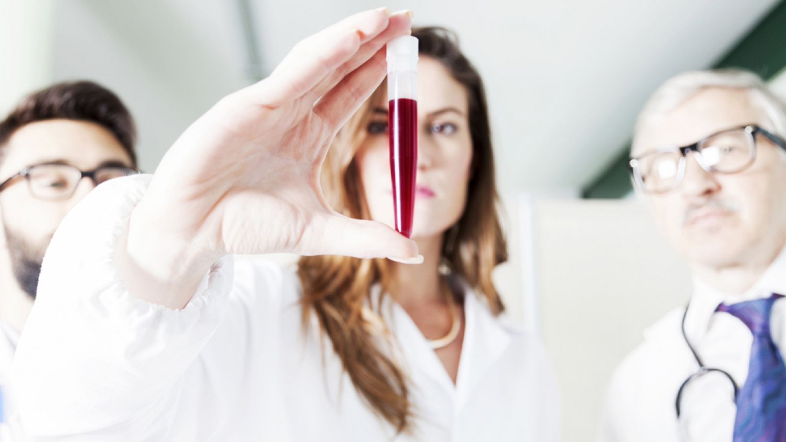 Tres científicos examinan una muestra de sangre en un laboratorio