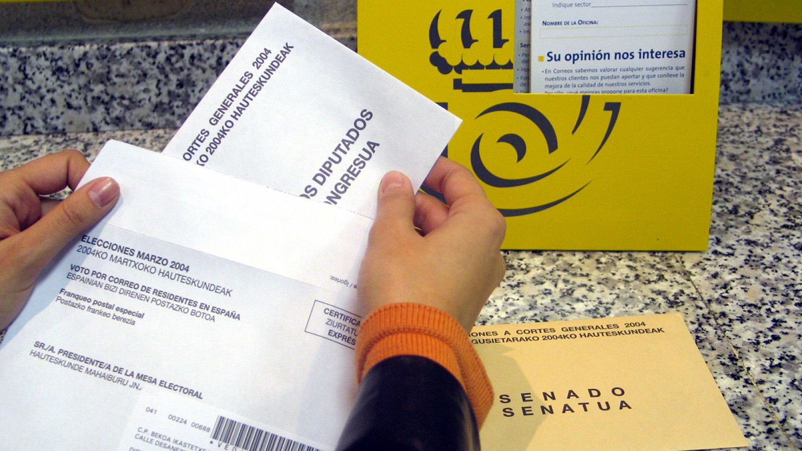 Imagen de archivo en el que una ciudadana deposita su voto por correo en una oficina postal.