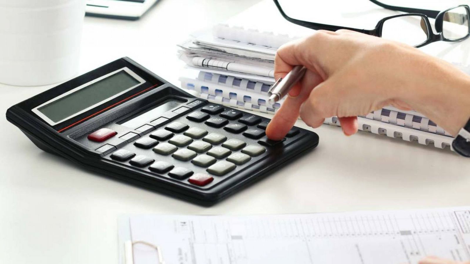 Una contable utilizando una calculadora para rellenar un impreso tributario