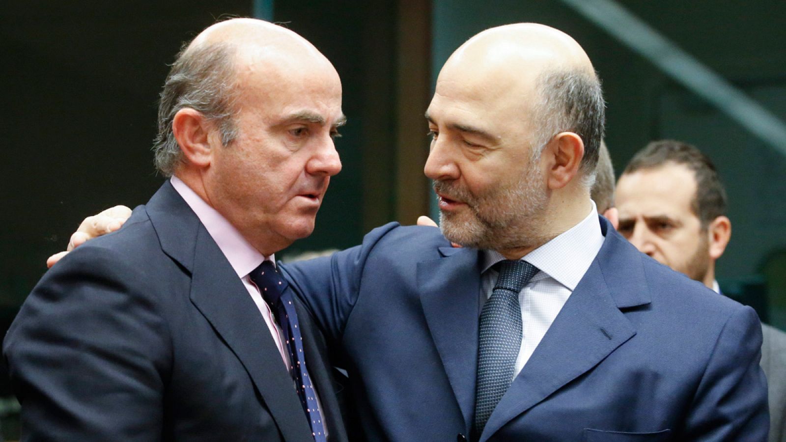 El ministro español de Economía, Luis de Guindos, conversa con el comisario europeo de Asuntos Económicos, Pierre Moscovici, durante una reunión de los responsables de Economía y Finanzas de la zona euro
