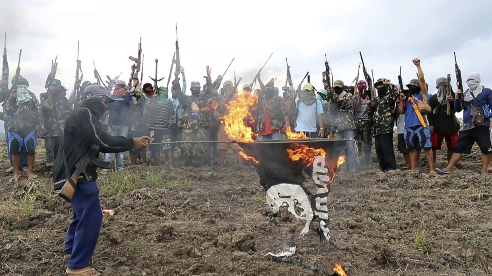 Miembros del grupo cristiano armado llamado "Defensores del Dios Rojo" queman una réplica de la bandera del EI en las montañas del centro de Mindalao (Filipinas)