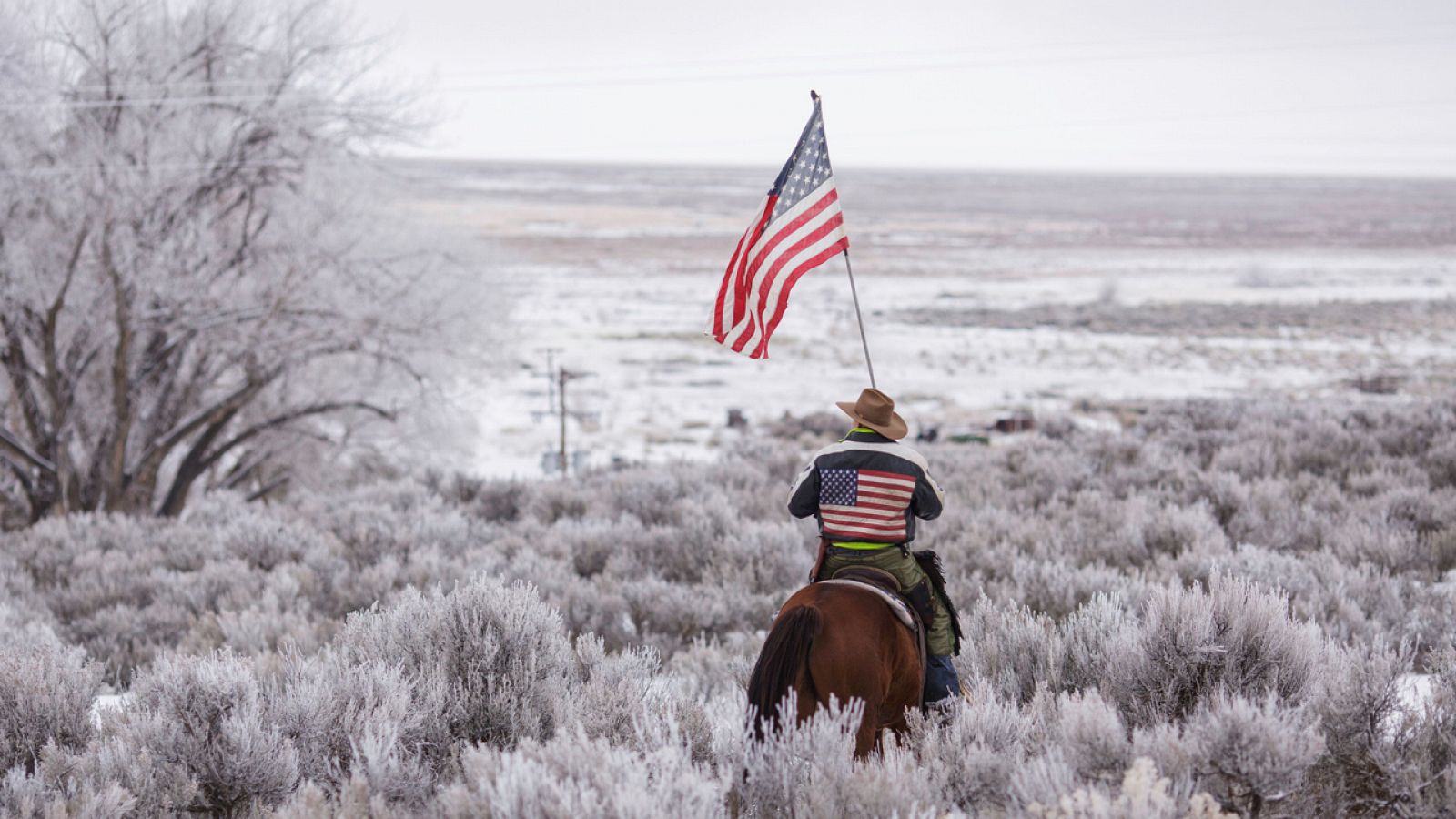 Un miembro de la milicia ocupante del parque natural Malheur en Oregón cabalga con una bandera estadounidense