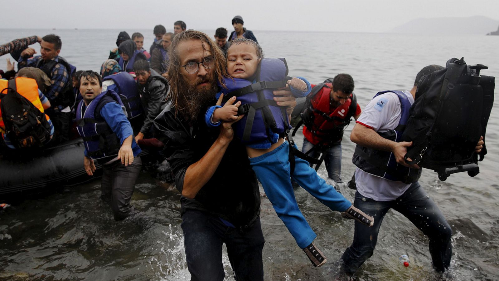 Un voluntario recoge a un niño sirio refugiado de una embarcación en la costa de Lesbos en Grecia