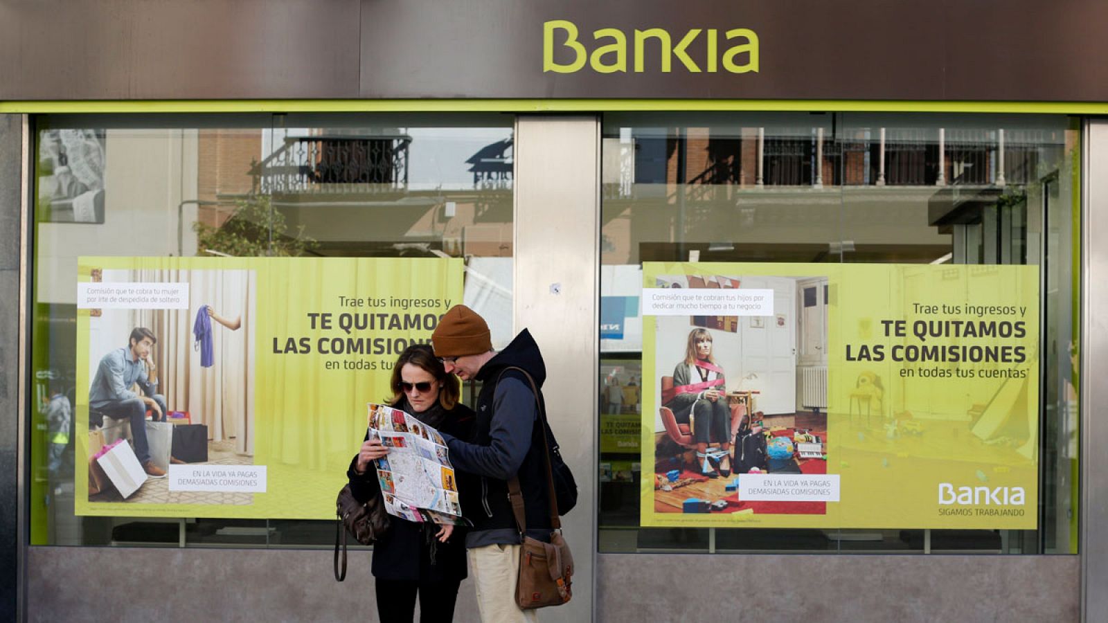 Dos turistas delante de una sucursal de Bankia