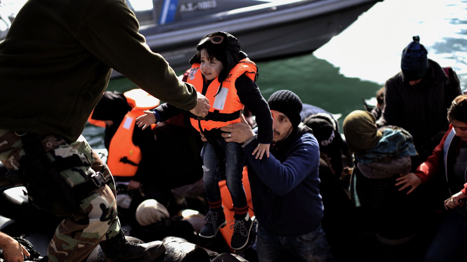 Un guardia costero griego ayuda a un menor refugiado a desembarcar en el puerto de Mytilene, en la isla griega de Lesbos