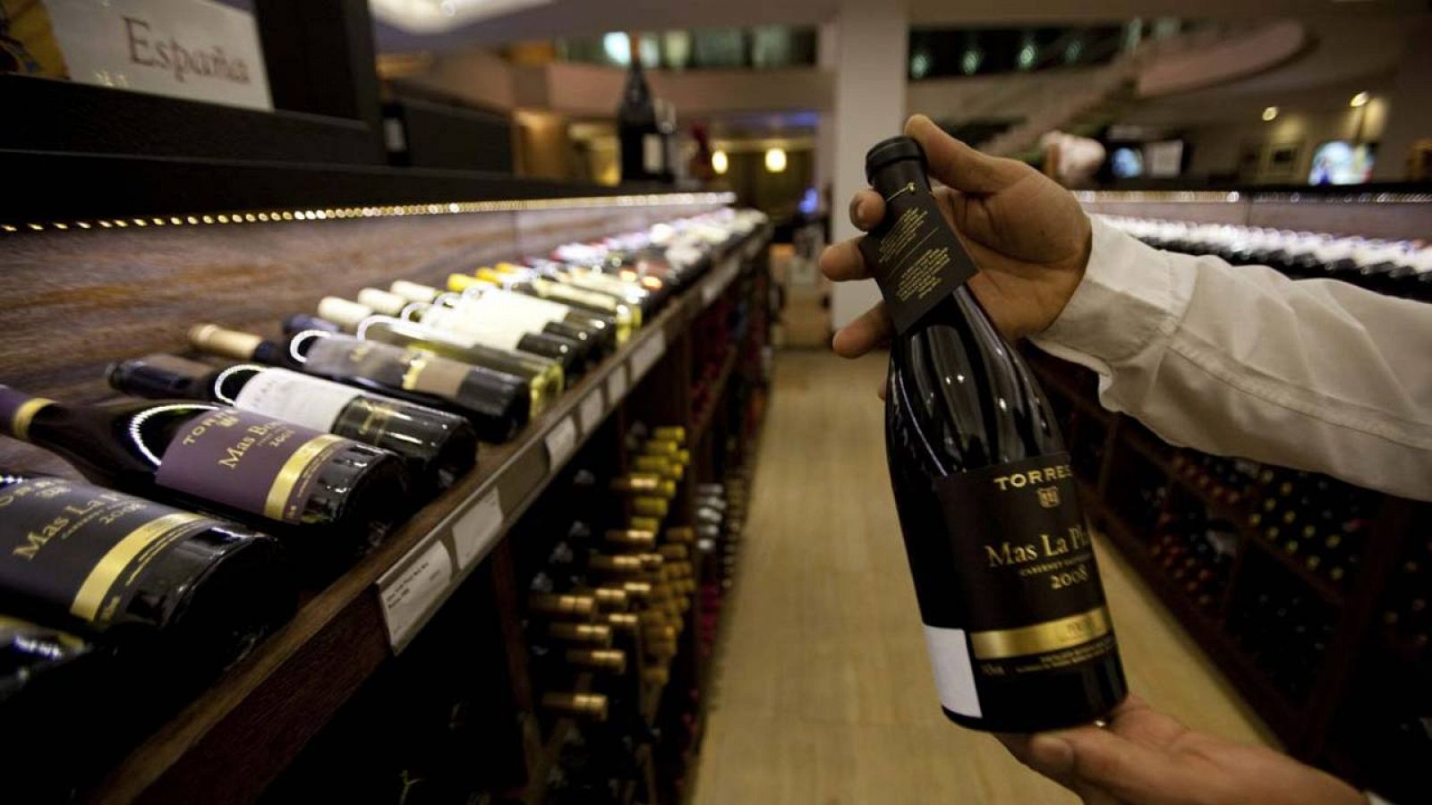 Un empleado de una tienda de vinos sostiene una botella de vino español
