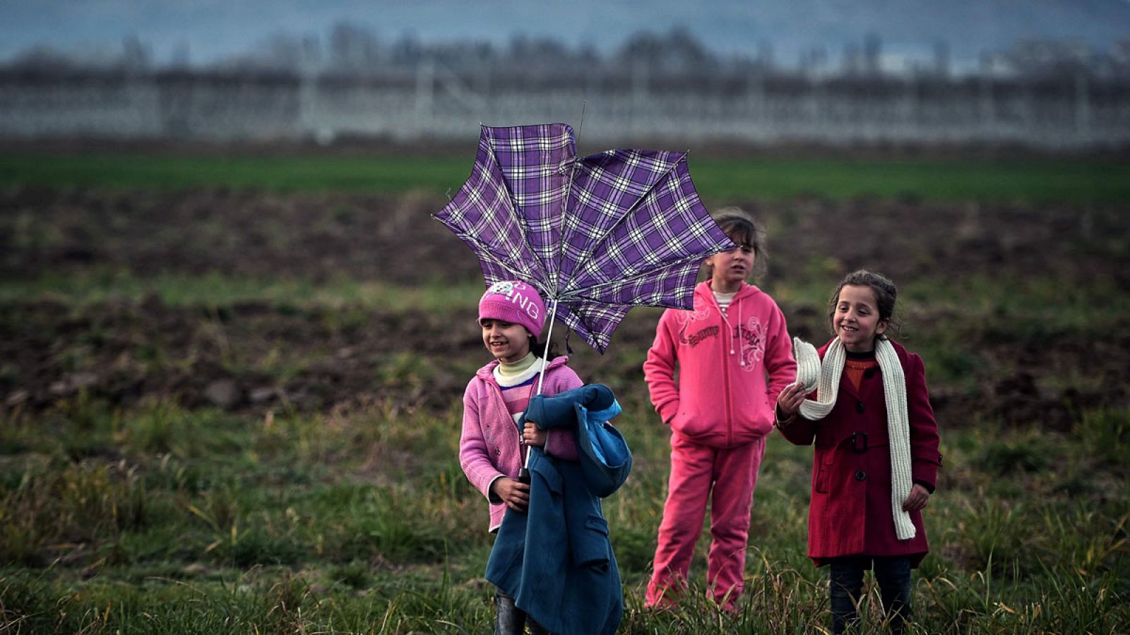 Niñas refugiadas juegan con un paragüas roto en la frontera entre Grecia y Macedonia.