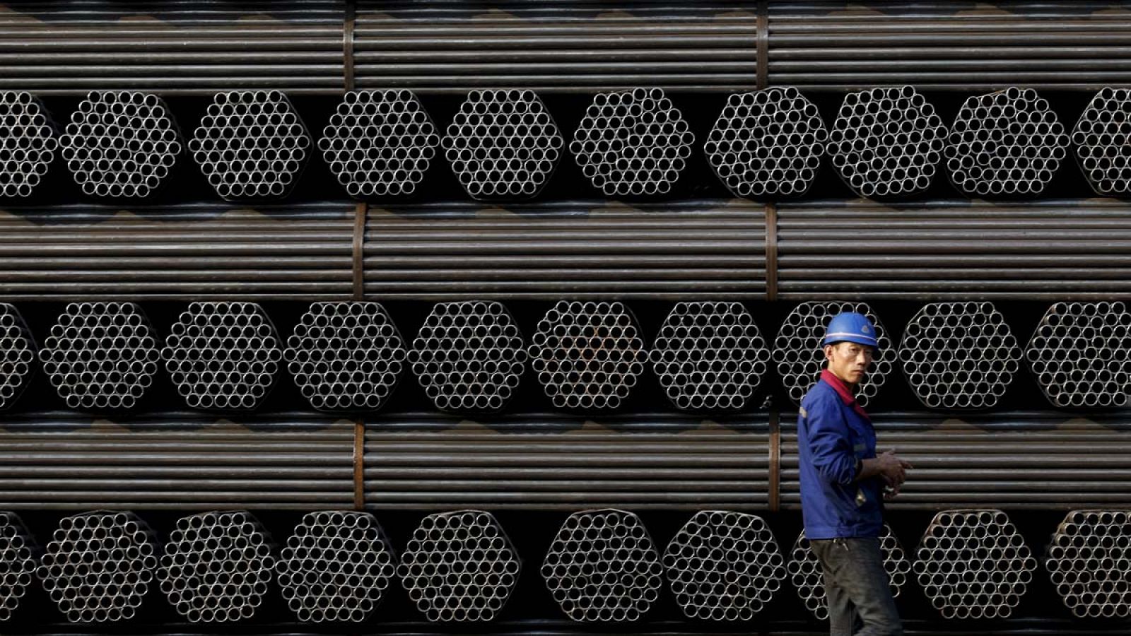 Un trabajador pasa delante de una pila de tubos de acero en la provincia china de Hebei
