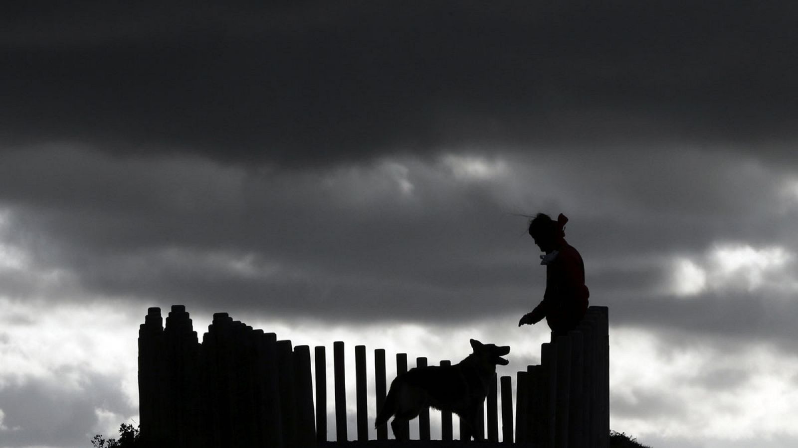 Una persona pasea junto a su perro  bajo un cielo bastante cubierto por el mirador de Ripagaina, junto a Pamplona.