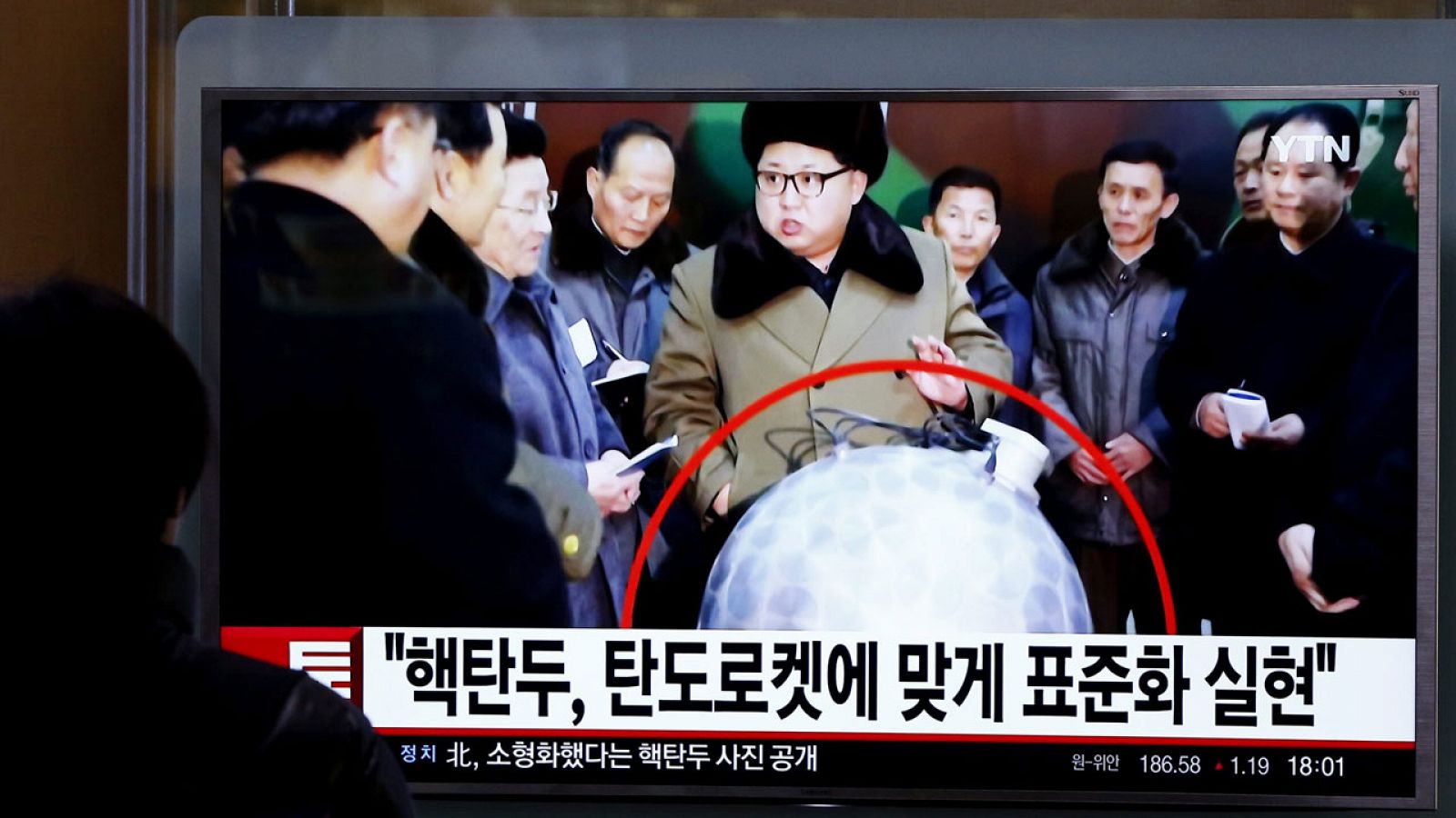 Un surcoreano observa la televisión donde se ve al líder de Corea del Norte con una réplica de una supuesta bomba nuclear.