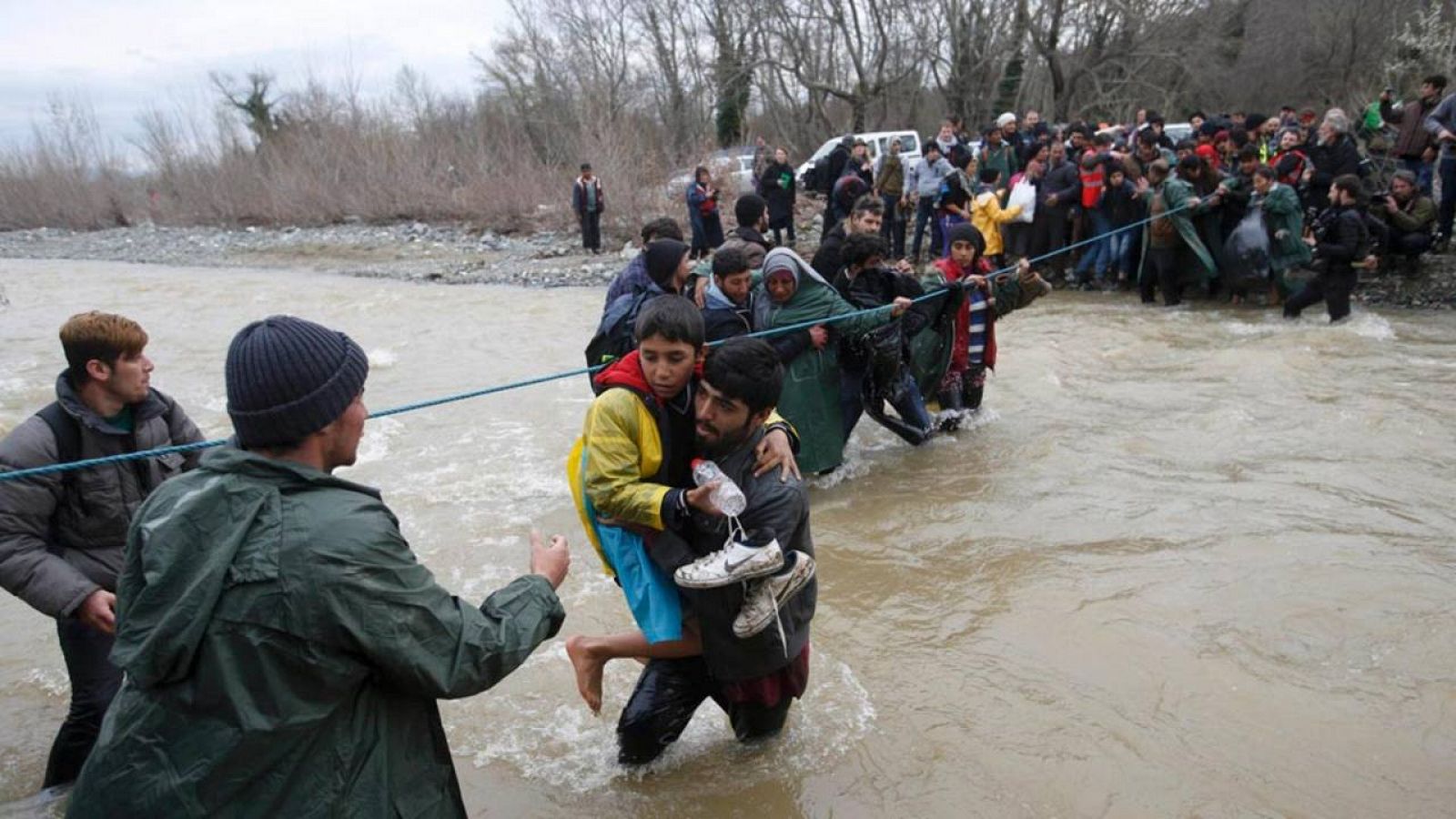 Un grupo de refugiados cruzan un río en la frontera entre Grecia y Macedonia