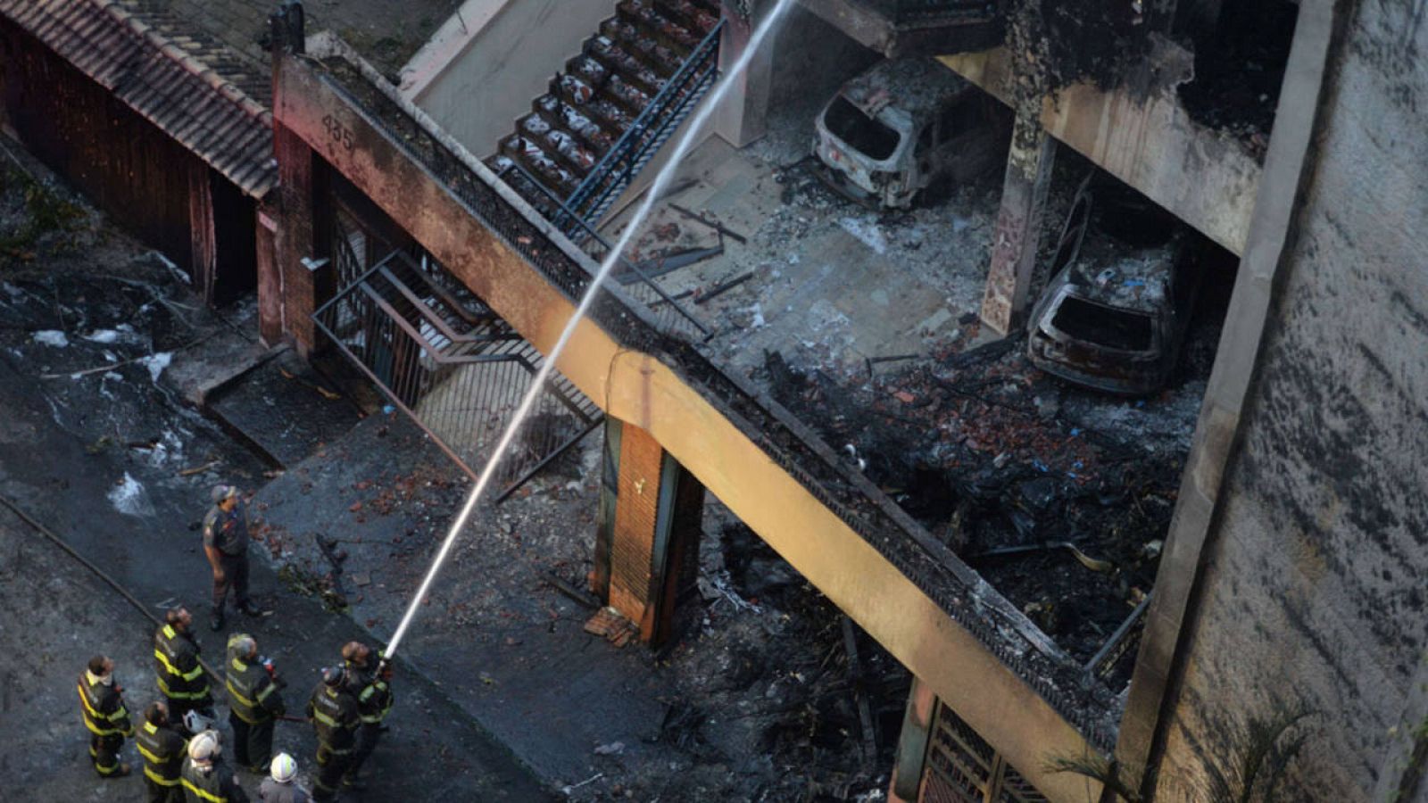 Imagen de los bomberos apagando las llamas originadas tras el impacto de la avioneta. 