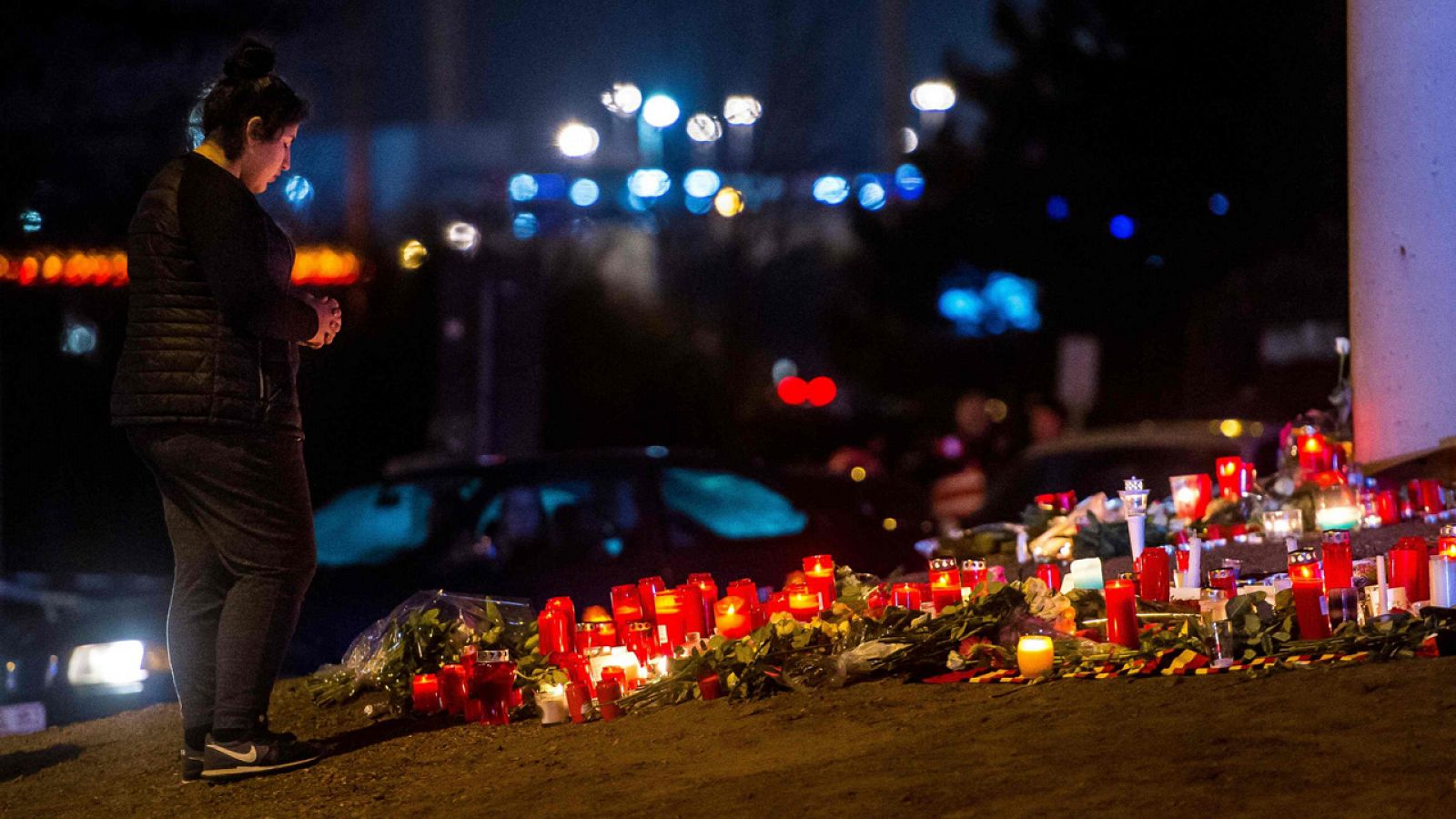 Una mujer reza en Bruselas delante de una ofrenda floral a las víctimas