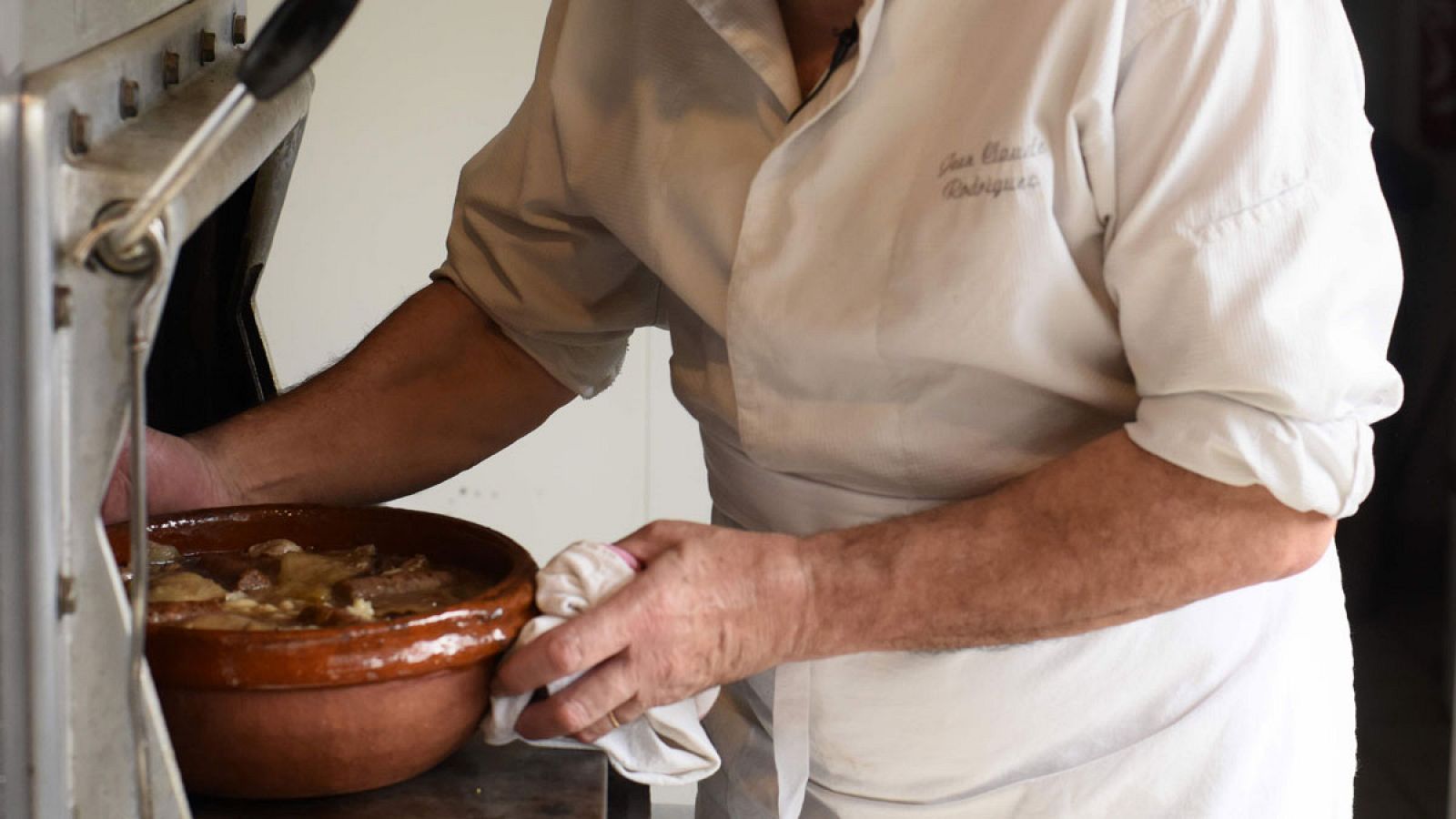 Un cocinero saca un guiso de un horno de gas