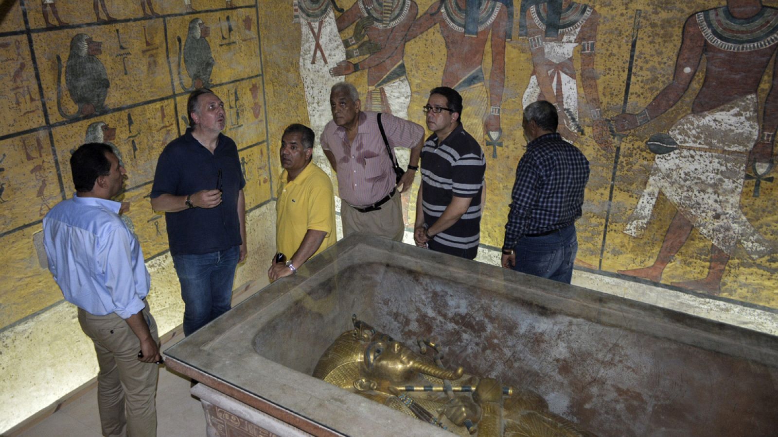 El egiptólogo británico Nicholas Reeves (2i) y el exministro de Antigüedades, Mamduh al Damati (3i), conversan frente al sarcófago de Tutankamón.