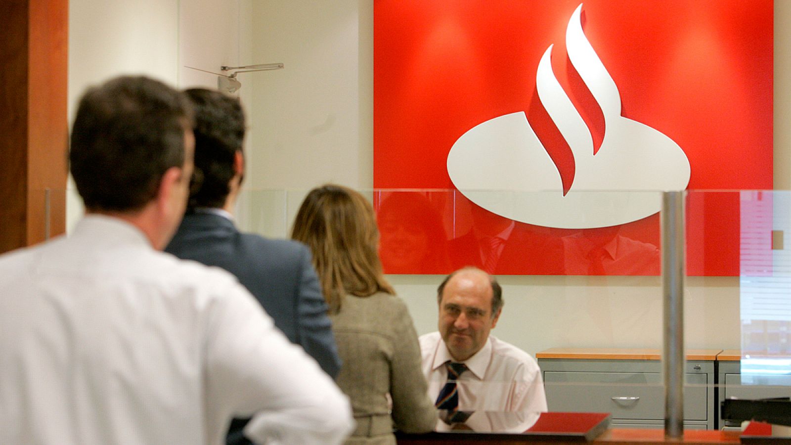 Imagen de archivo de un empleado atendiendo clientes en una oficina del Banco Santander.