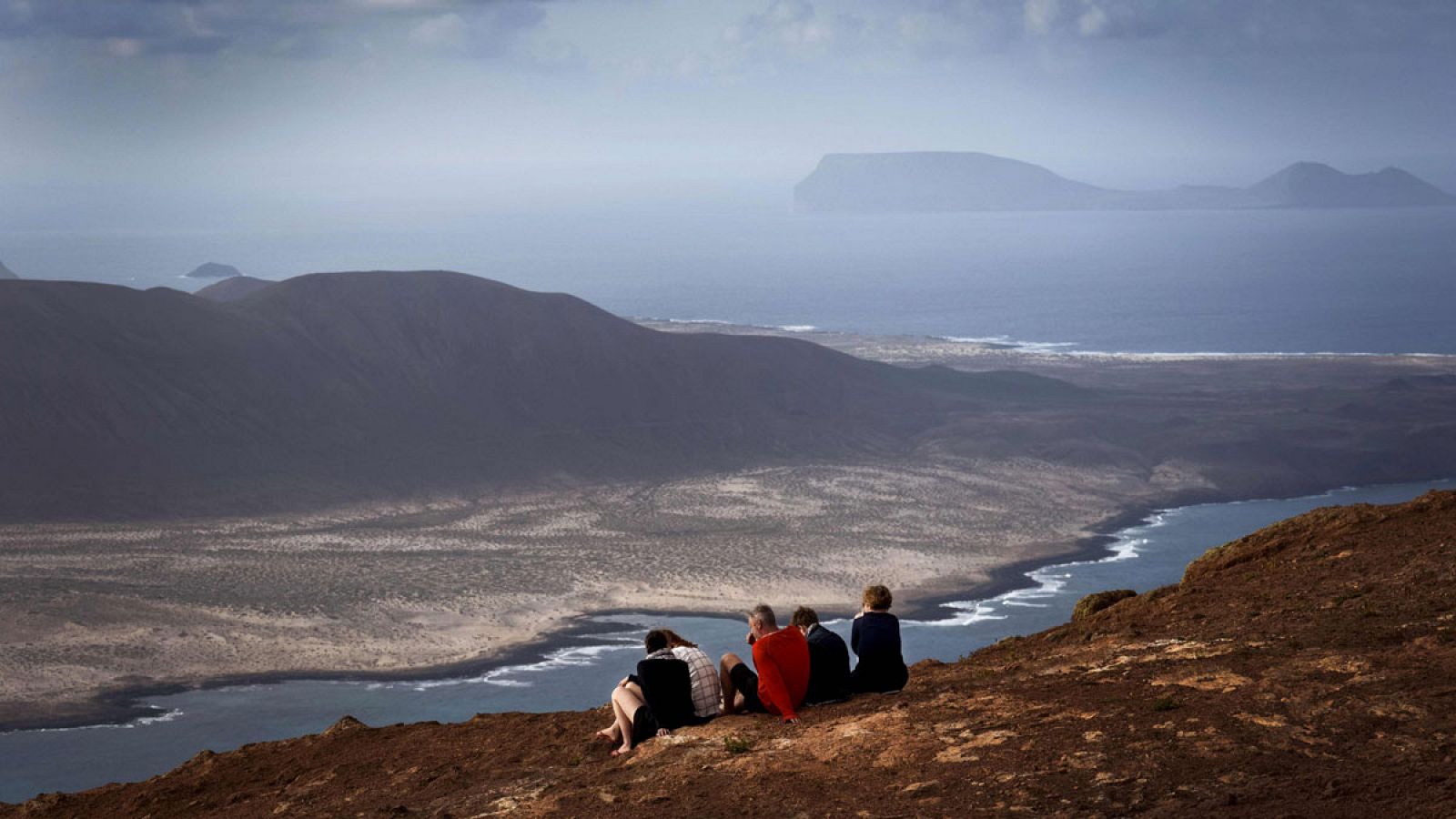 Unos turistas observan desde Lanzarote la isla de La Graciosa