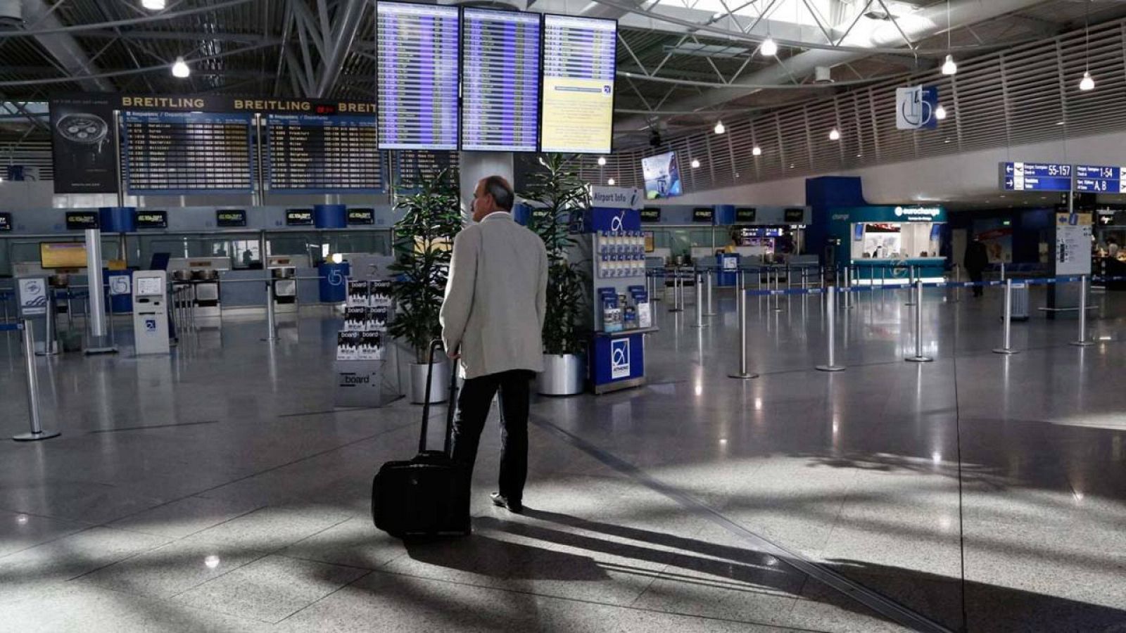 Un pasajero, de pie ante un panel informativo en el vestíbulo de facturación del aeropuerto ateniense, desierto este jueves a consecuencia de la huelga
