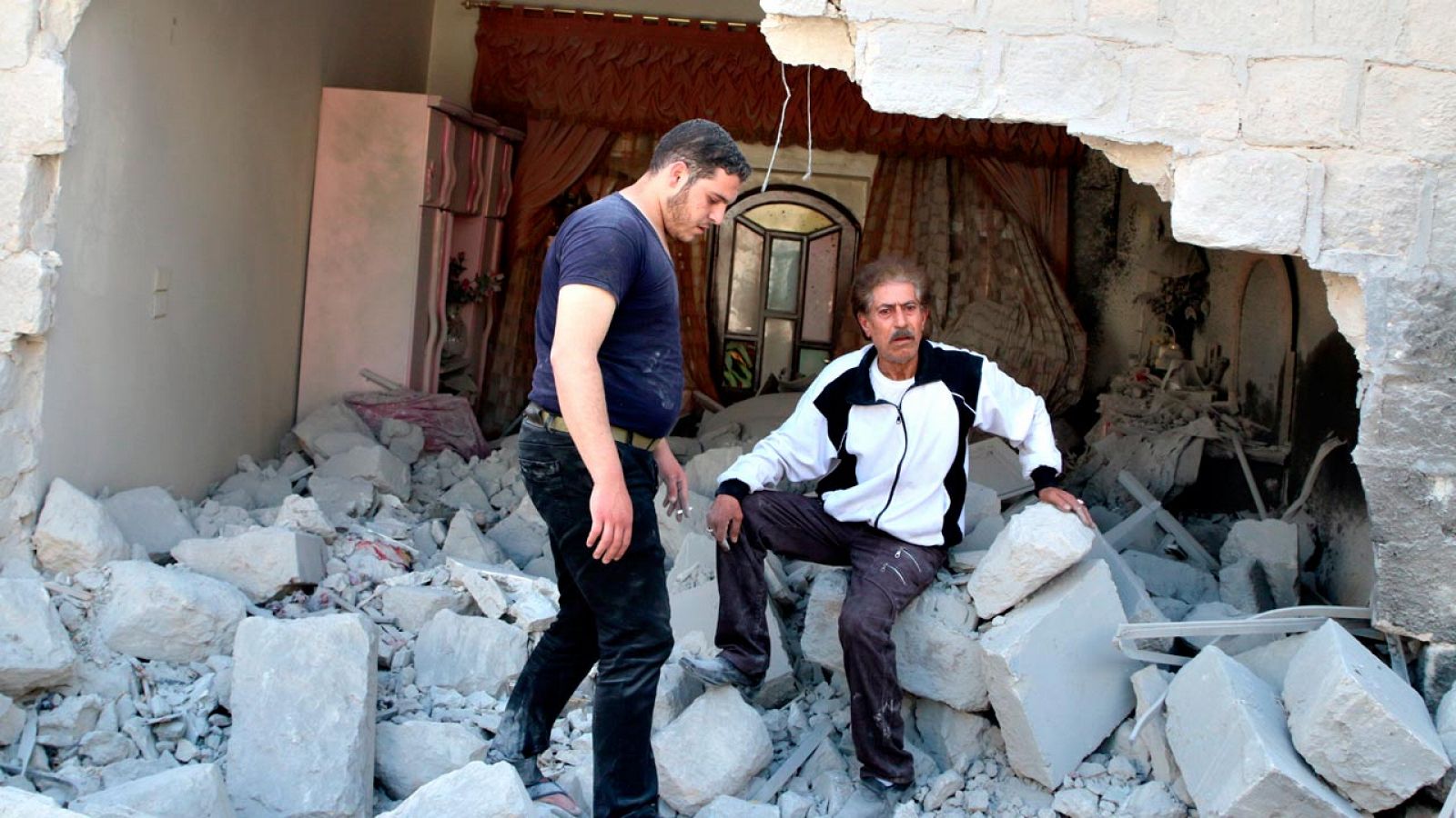 Dos hombres se lamentan en Alepo tras un bombardeo de las fuerzas gubernamentales