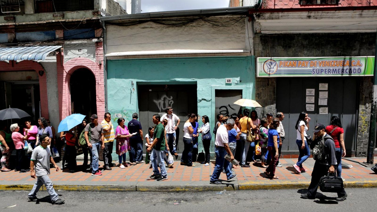 Ciudadanos venezolanos hacen cola para comprar productos básicos en un supermercado de Caracas