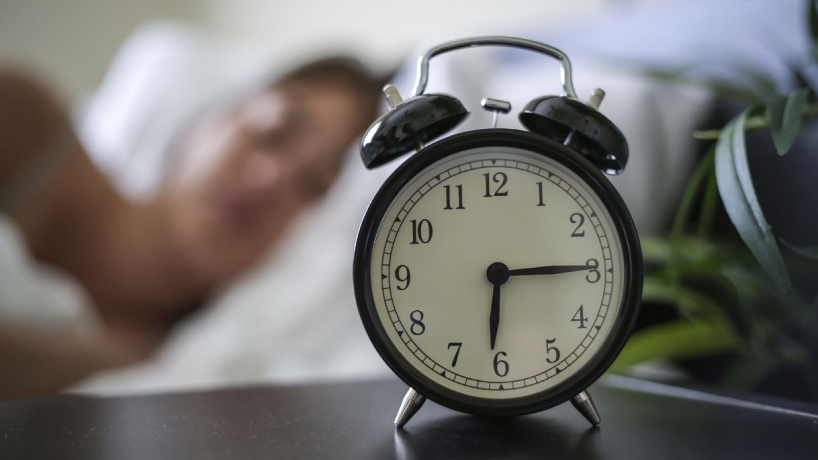 Imagen recurso de una persona durmiendo tras un despertador