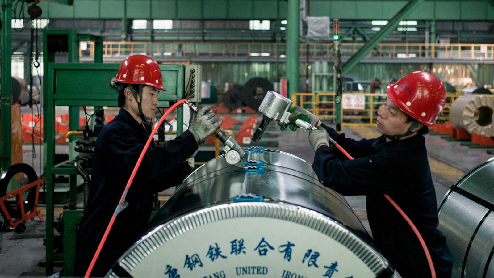 Dos trabajadores chinos preparan una bobina de acero laminado