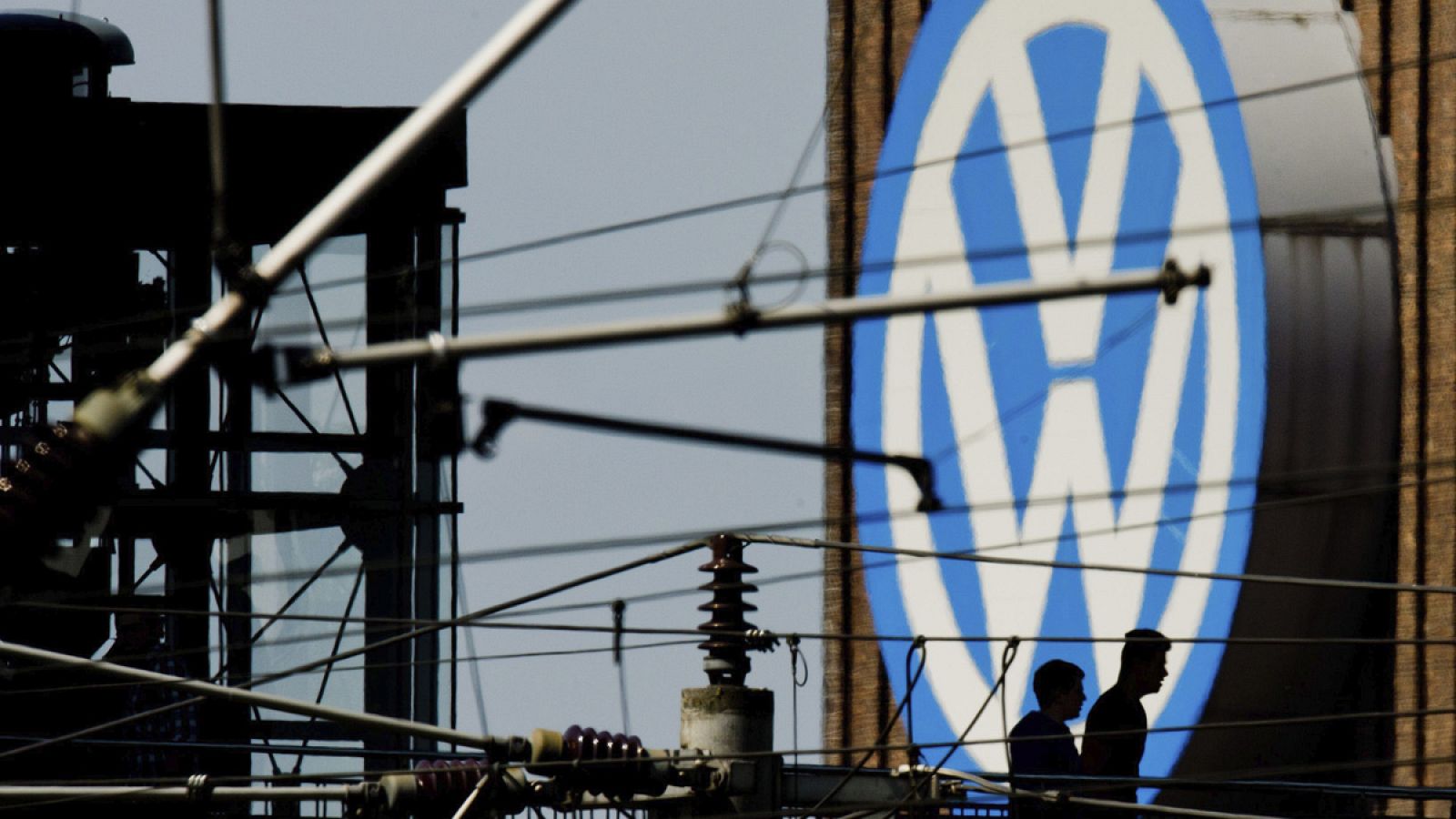 Dos hombres caminan junto al logotipo de Volkswagen en la fábrica de Hannover, Alemania