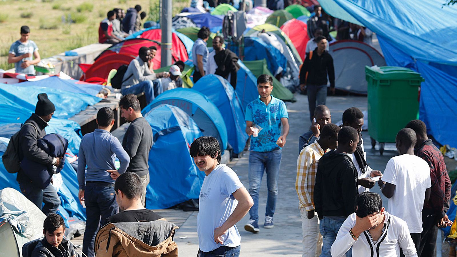 Un grupo de refugiados camina entre las tiendas de campaña de un campamento improvisado en París.