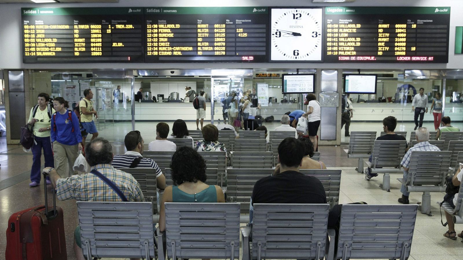 Varios pasajeros esperan la llegada de sus trenes ante las pantallas informativas en la estación de Chamartín, en Madrid