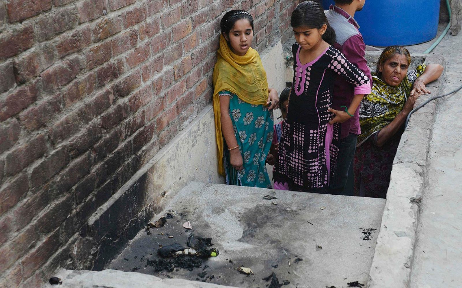 Varios vecinos observan el lugar en que la joven Zeenat Bibi fue quemada por su madre, en la ciudad paquistaní de Lahore