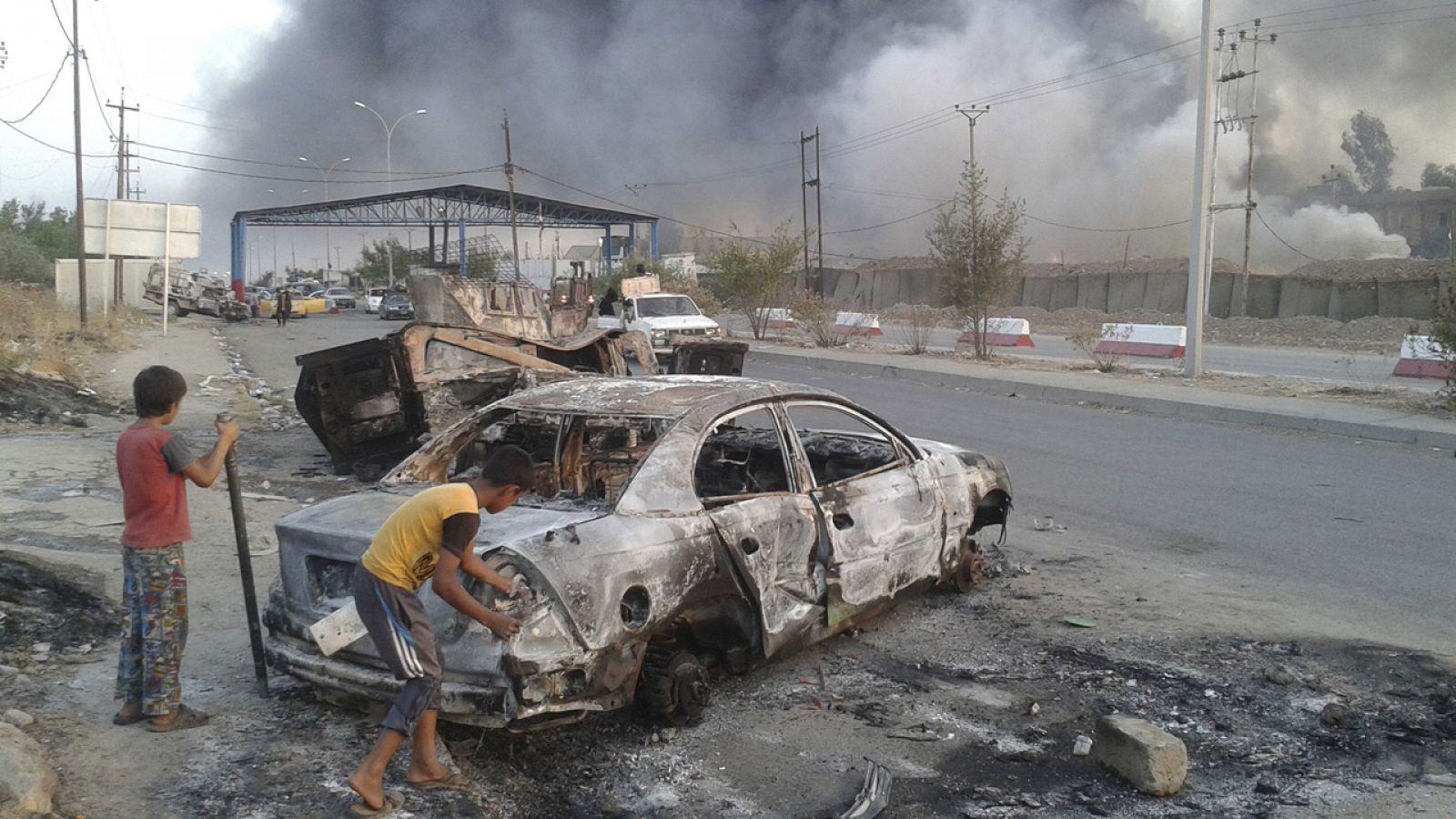 Niños de Mosul juegan junto a un vehículo quemado tras los enfrentamientos entre el ejército iraquí y los yihadistas del EI