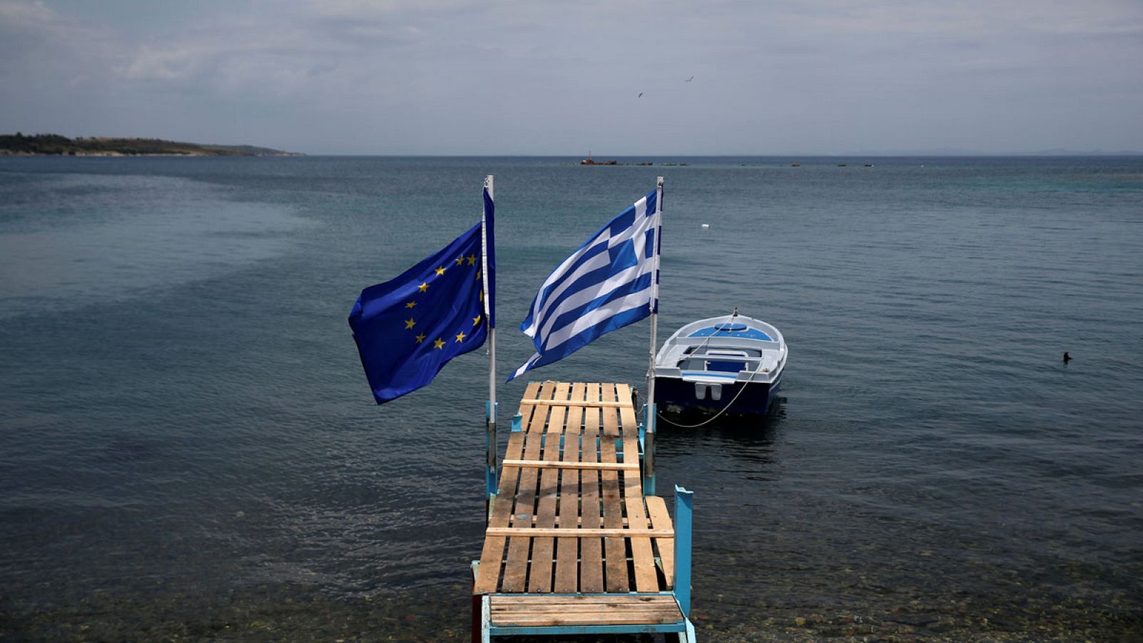 Un embarcadero con la bandera griega y la de la UE