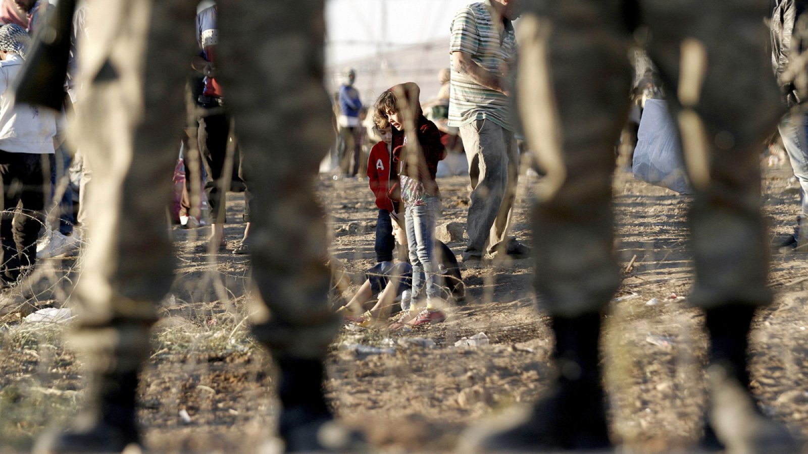 Refugiados sirios ante los militares que guardan la frontera con Turquía