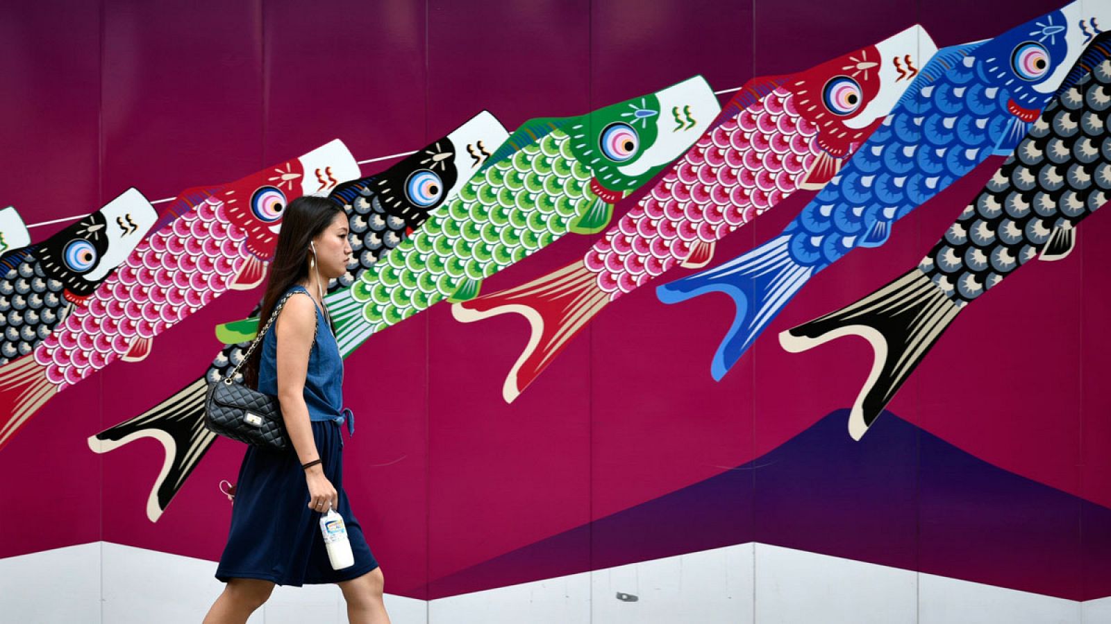 Una mujer pasa delante de un andamio decorado con dibujos de peces en el distrito comercial de Ginza en Tokio