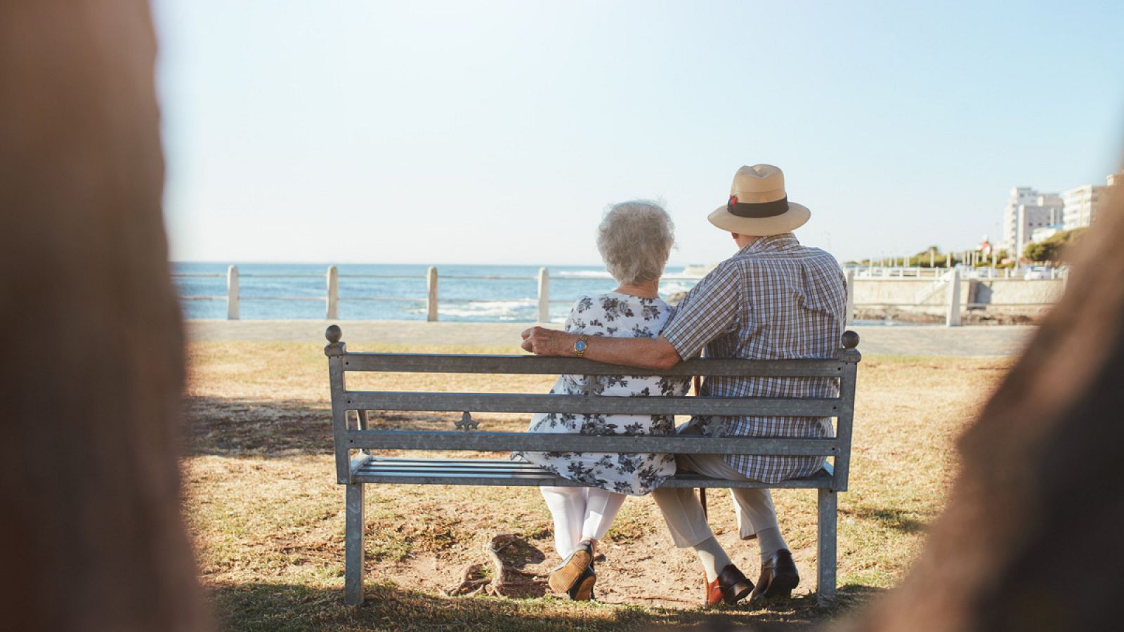 Dos jubilados sentados en un banco en la playa