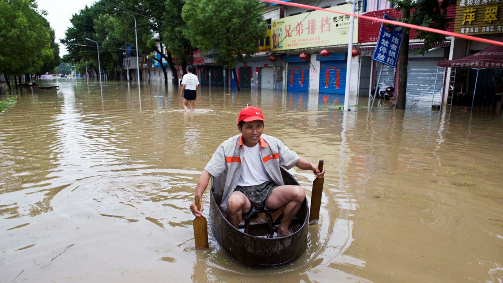 Un ciudadano rema en una barca improvisada por las calles inundadas de Chaohu, China