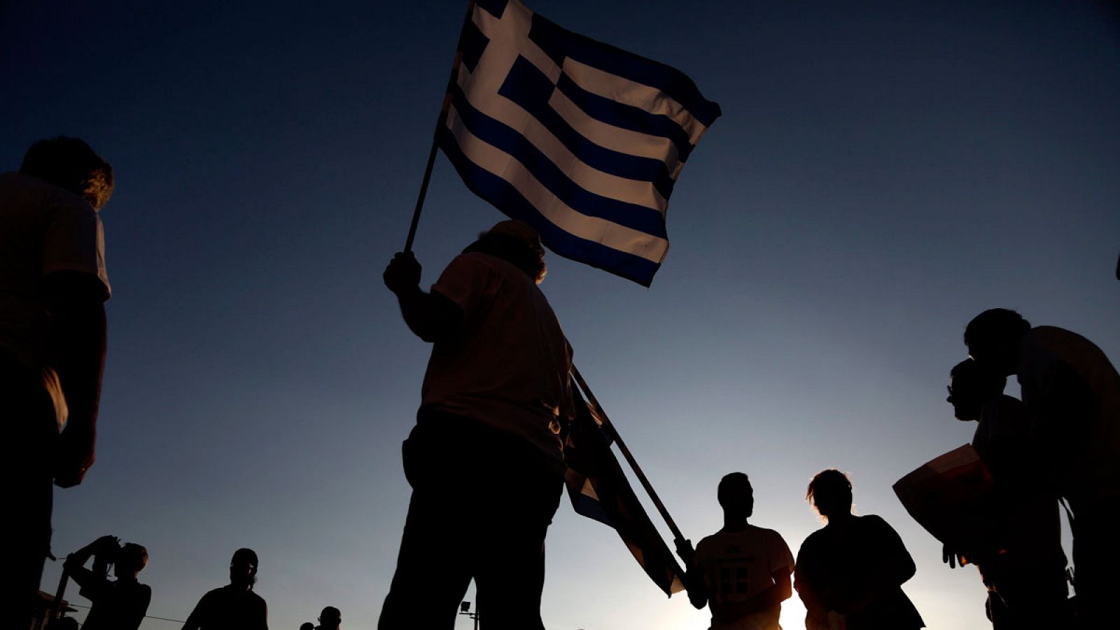 Manifestantes antigubernamentales enarbolan una bandera de Grecia