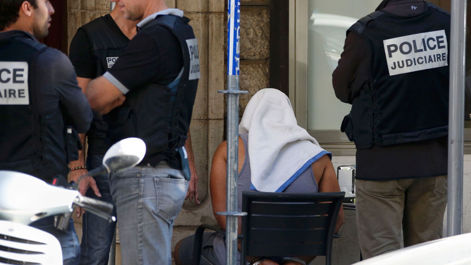Uno de los detenidos en relación con el atentado de Niza esposado y cubierto con una toalla