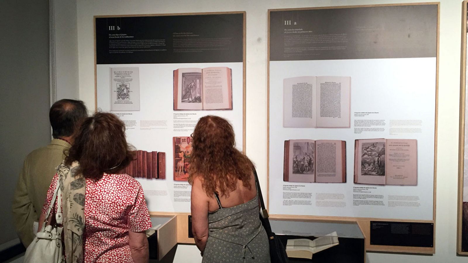 Tres personas observan las diferentes traducciones de Don Quijote de la Mancha durante la inauguración de la exposición "Quijotes por el mundo" en el Instituto Cervantes de Nueva York.