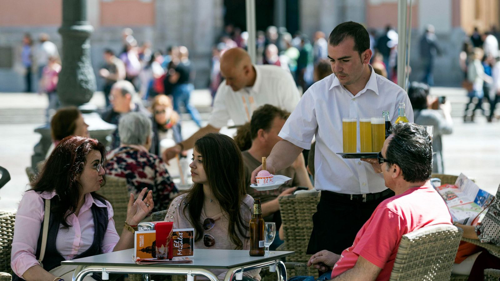 Un camarero sirve bebidas en una terraza en la plaza de la Virgen de Valencia.