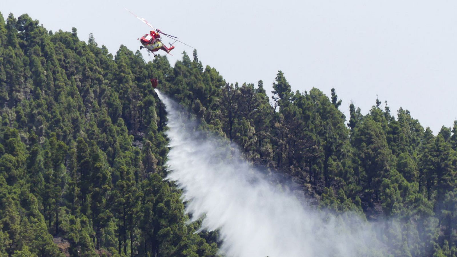 Un helicóptero enfría la zona quemada en La Palma