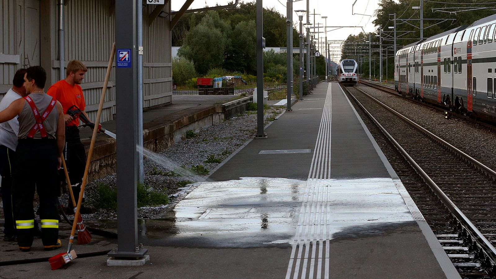 Varios trabajadores limpian el anden donde se detuvo el tren tras el ataque en Suiza