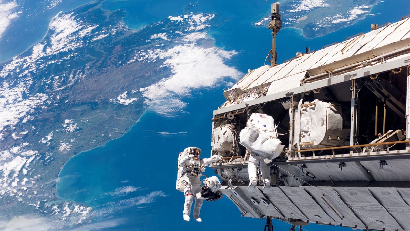 Imagen de dos astronautas trabajando en el exterior de la Estación Espacial Internacional.
