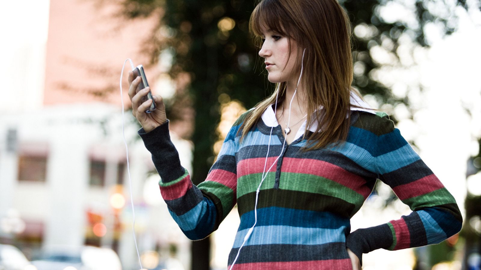 Una mujer escuchando un podcast por la calle.