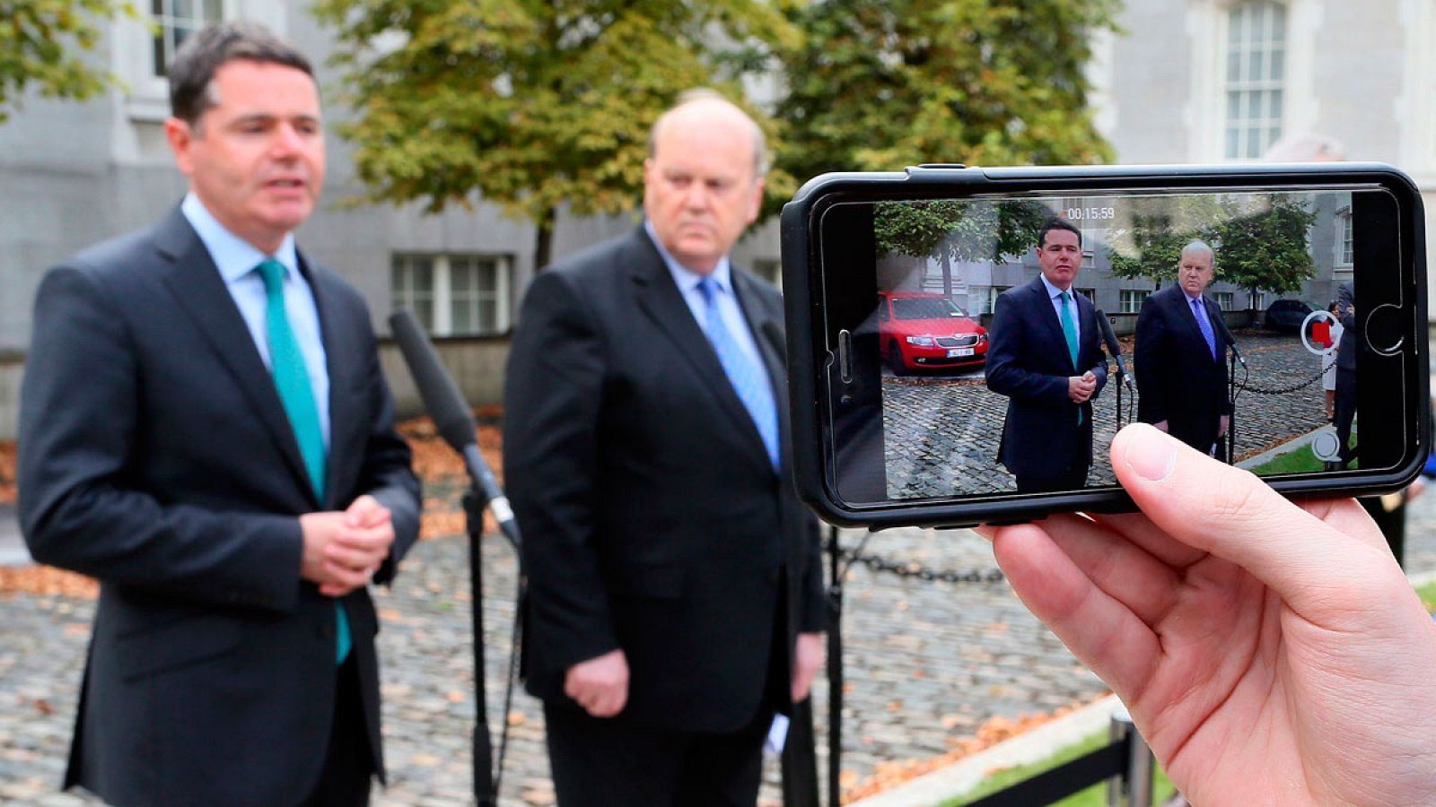El ministro de Economía de Irlanda, Michael Noonan, y el ministro de Gasto Público, Paschal Donohoe, en rueda de prensa mientras son fotografiados con un iPhone