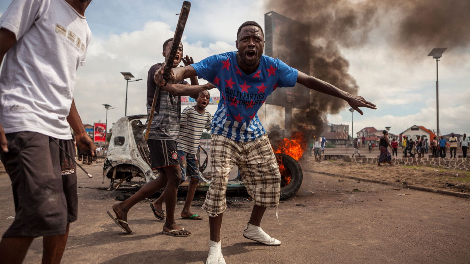 Manifestantes protestan junto a un coche ardiendo en Kinshasa, Repíblica Democrática del Congo