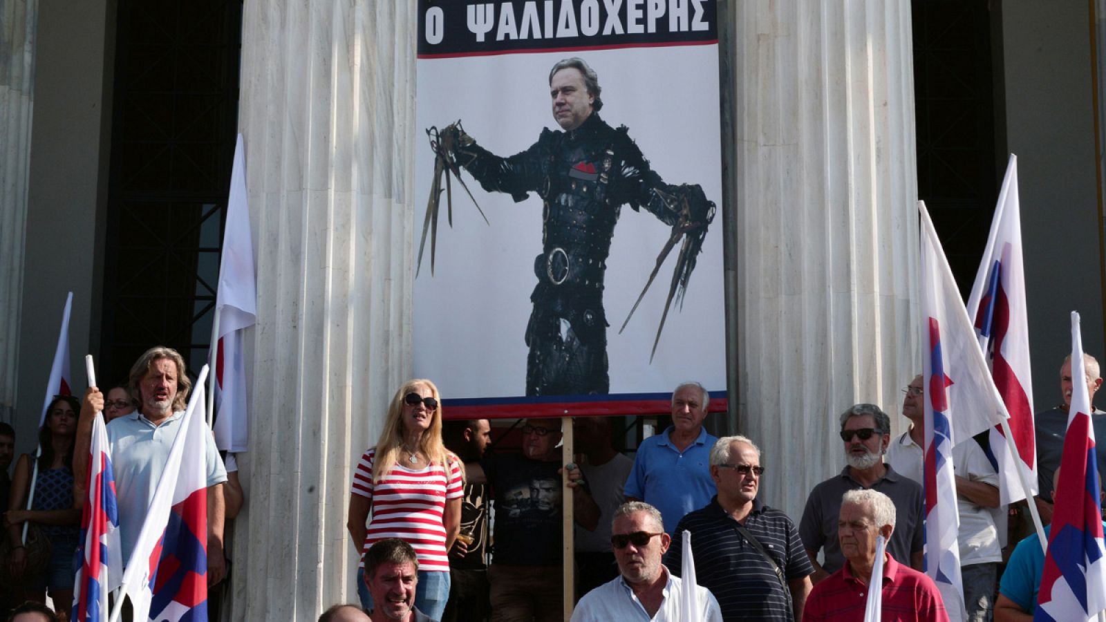 Una protesta en Atenas contra los recortes en la que se puede ver una pancarta con el ministro griego de trabajo, George Katrougalos, caracterizado como el personaje de ficción Eduardo Manostijeras
