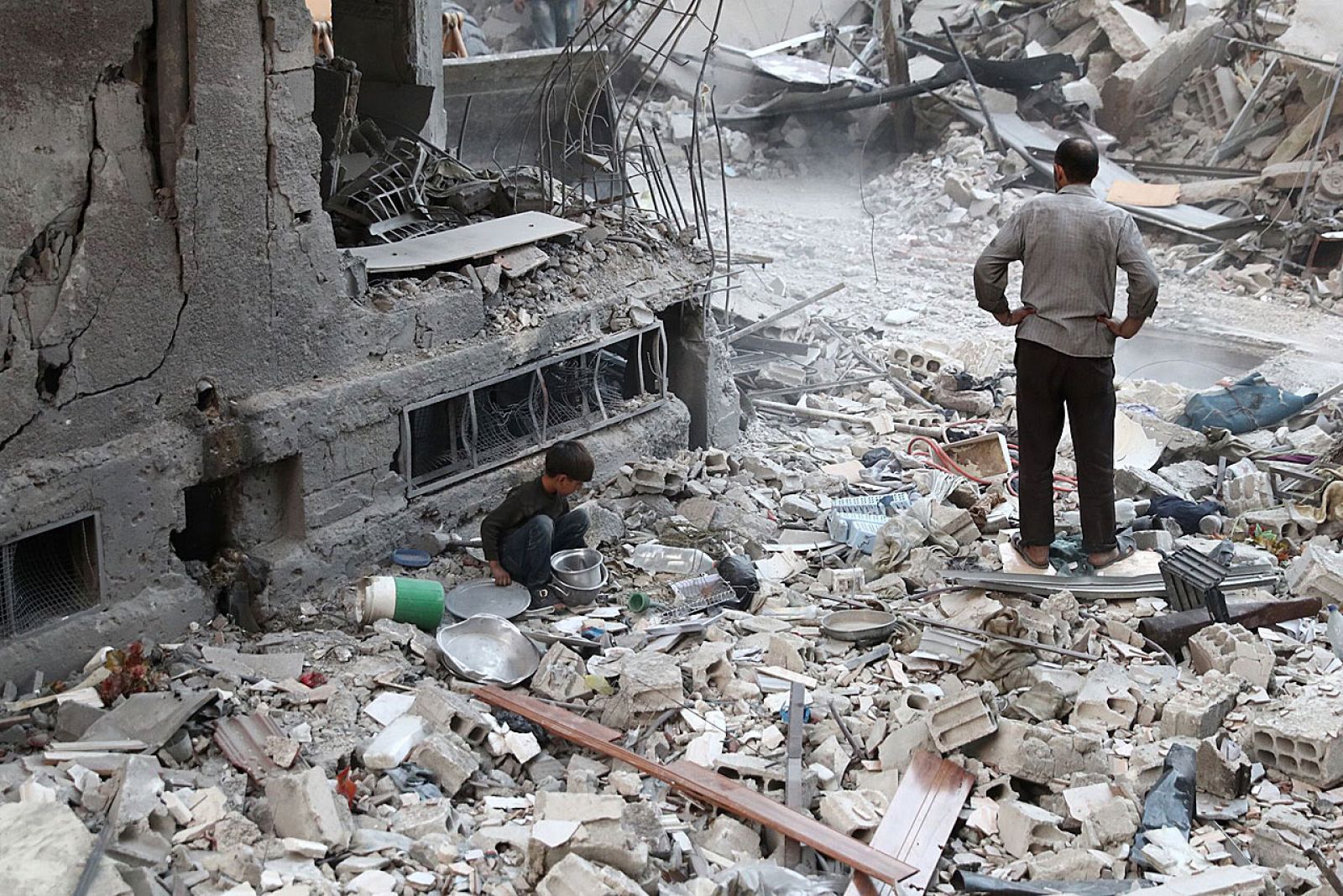 Un niño sirio recoge restos entre los escombros de un bombardeo en un suburbio en Damasco.