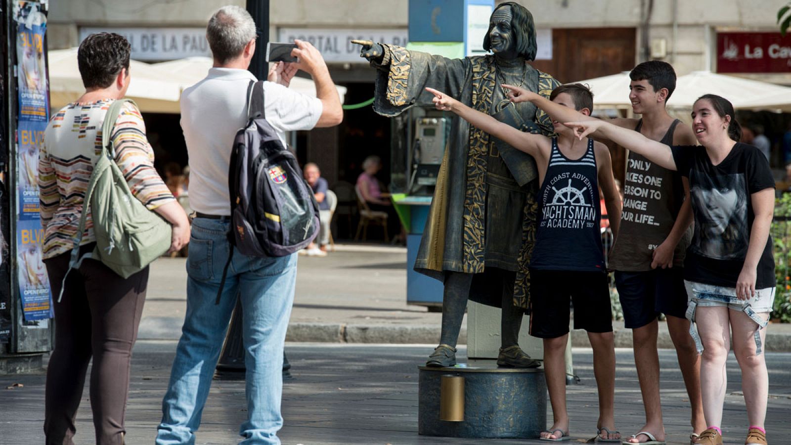 Unos turistas se fotografían en Barcelona con una estatua viviente de Colón